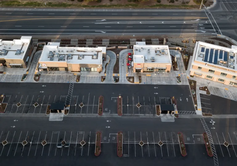 Aerial view of an empty parking lot in front of several buildings. Behind the buildings there is an empty street.