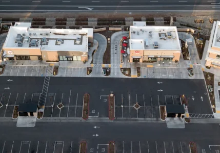 Aerial view of an empty parking lot in front of several buildings. Behind the buildings there is an empty street.