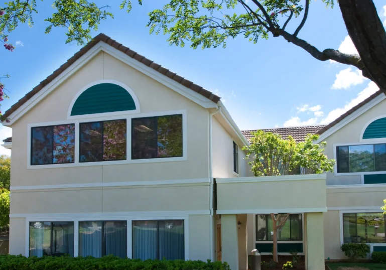 A house under a tree with a blue sky in the background.