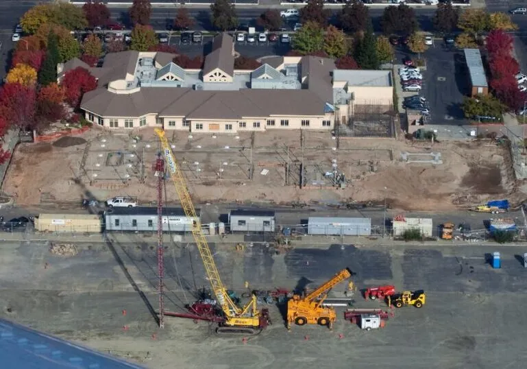 Aerial view of a large house under construction. A crane and other construction vehicles are outside.
