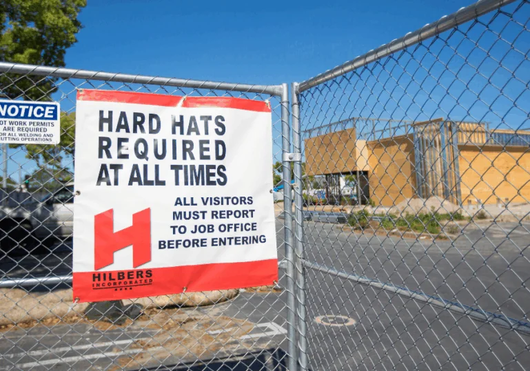 Sign reading “Hard Hats Required” at an active job site, reinforcing a strong safety culture and ongoing training for all team members.