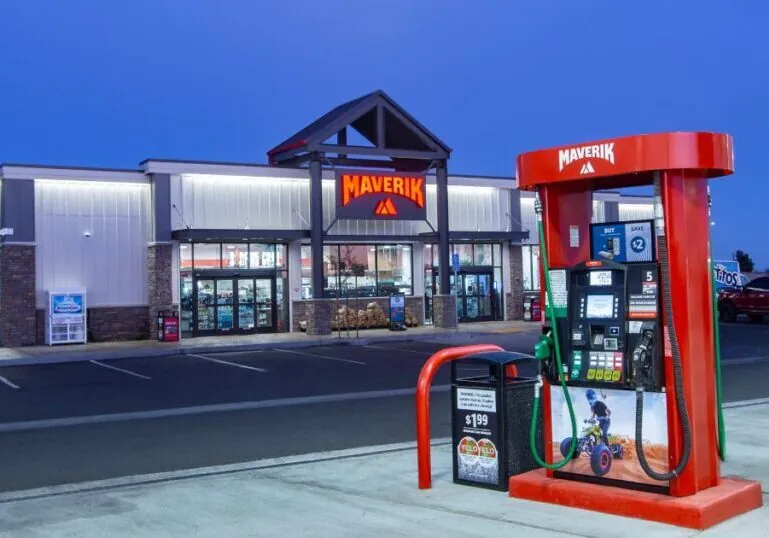 A red Maverik gas station pump at night. There is a Maverik store in the background.